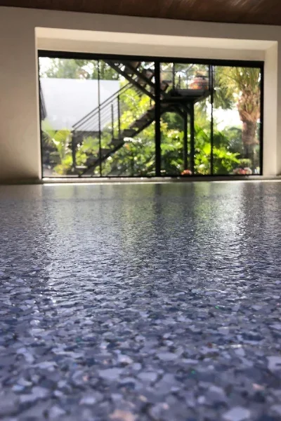 Polished dark aggregate concrete floor in modern room with large glass doors and windows