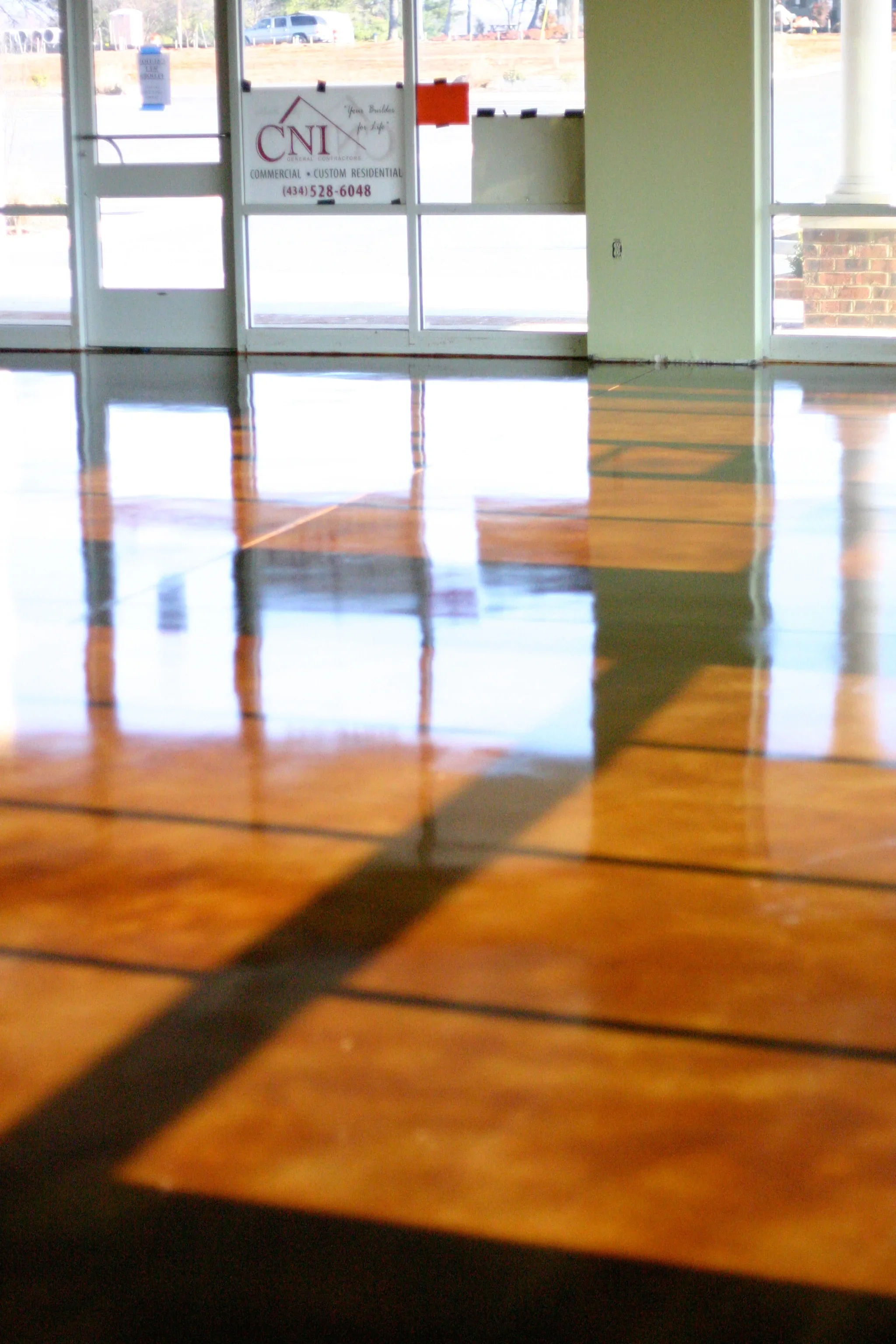 Polished epoxy-coated concrete floor with high-gloss finish and dark control joints in retail space