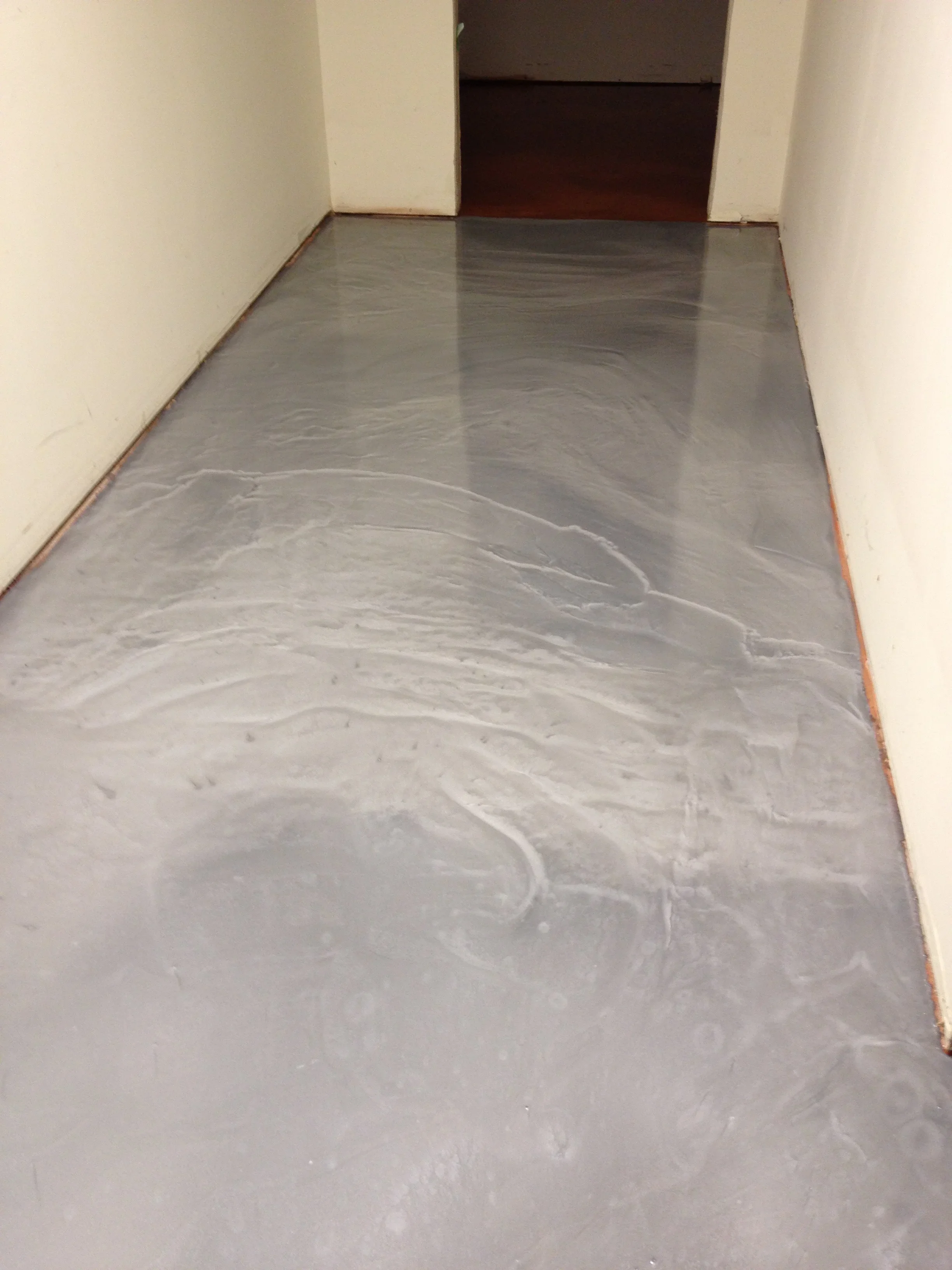 Gray epoxy floor coating with swirl patterns on concrete entryway