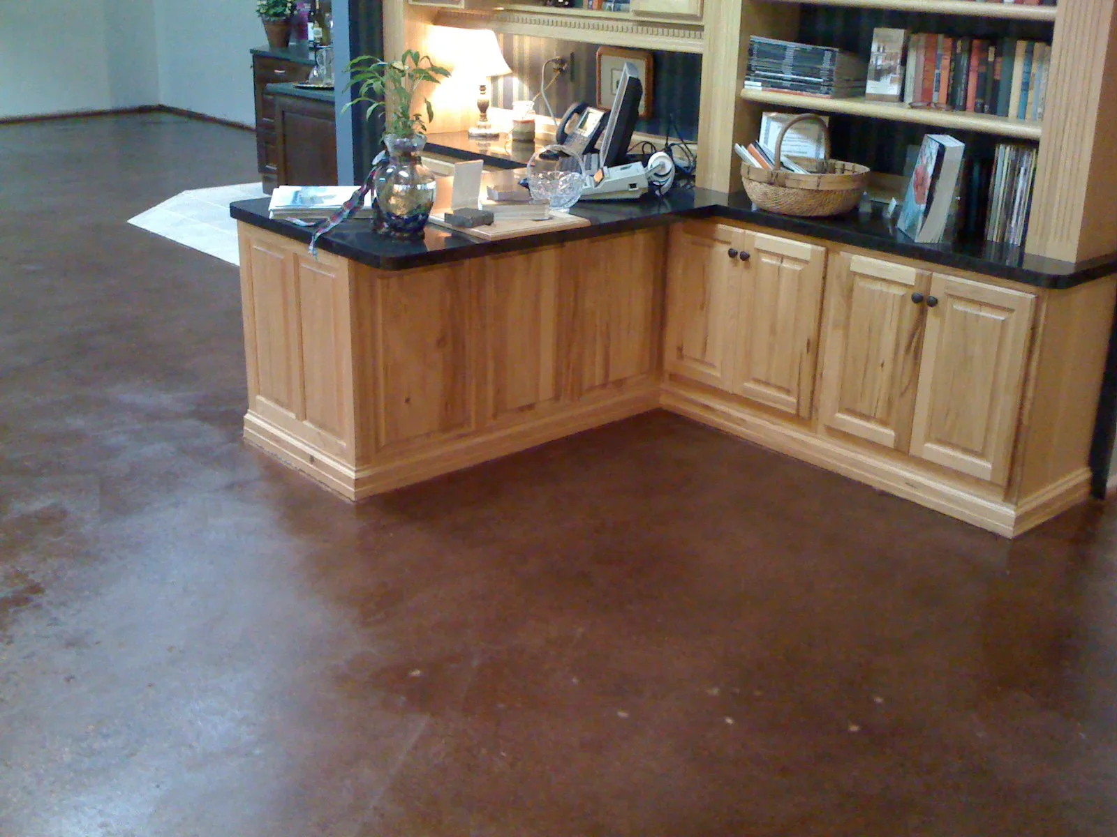 Polished brown concrete floor in office with wood cabinetry and shelving