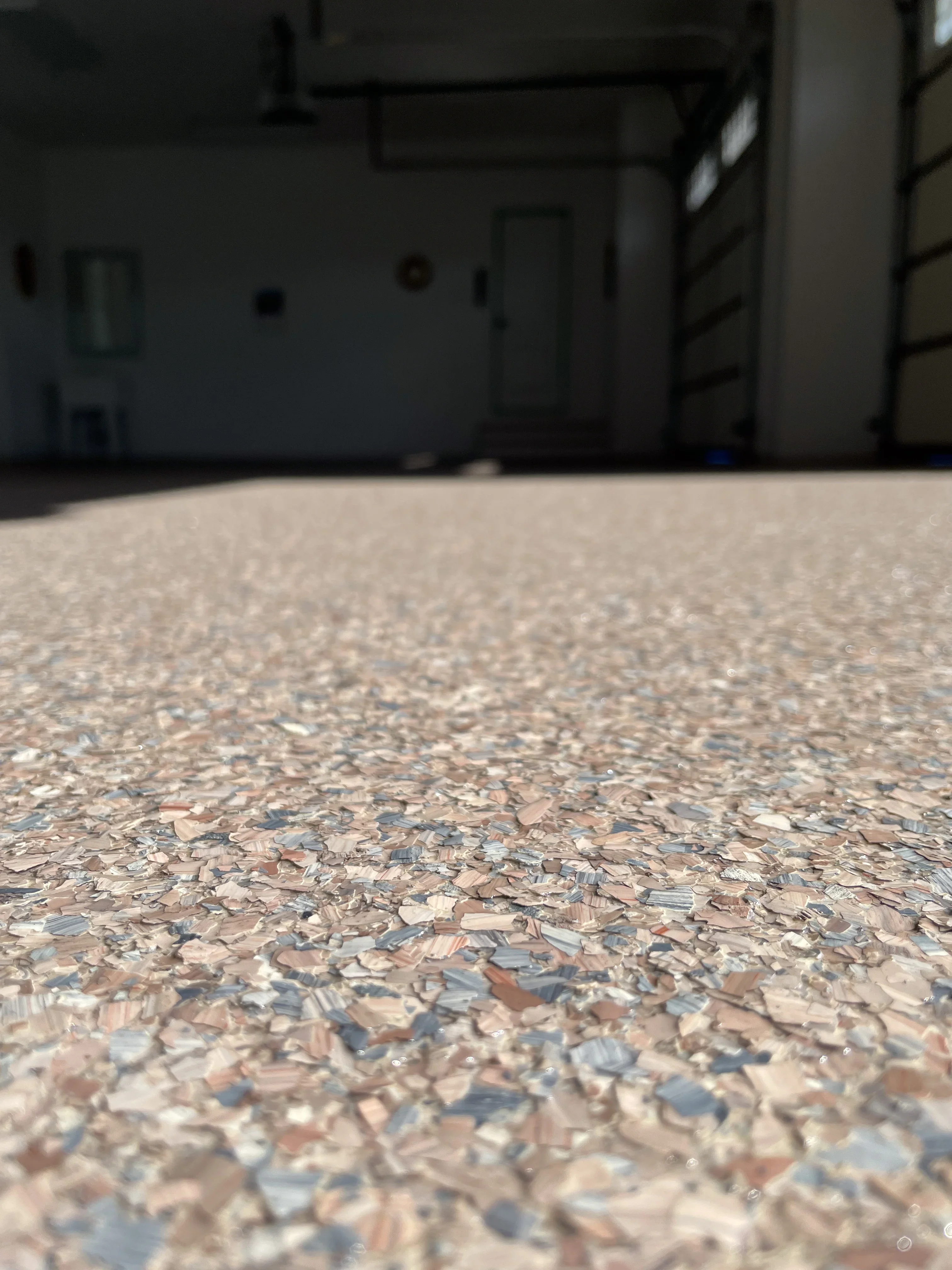 Close-up of decorative flake epoxy coating on garage floor with tan, brown, and blue aggregate chips