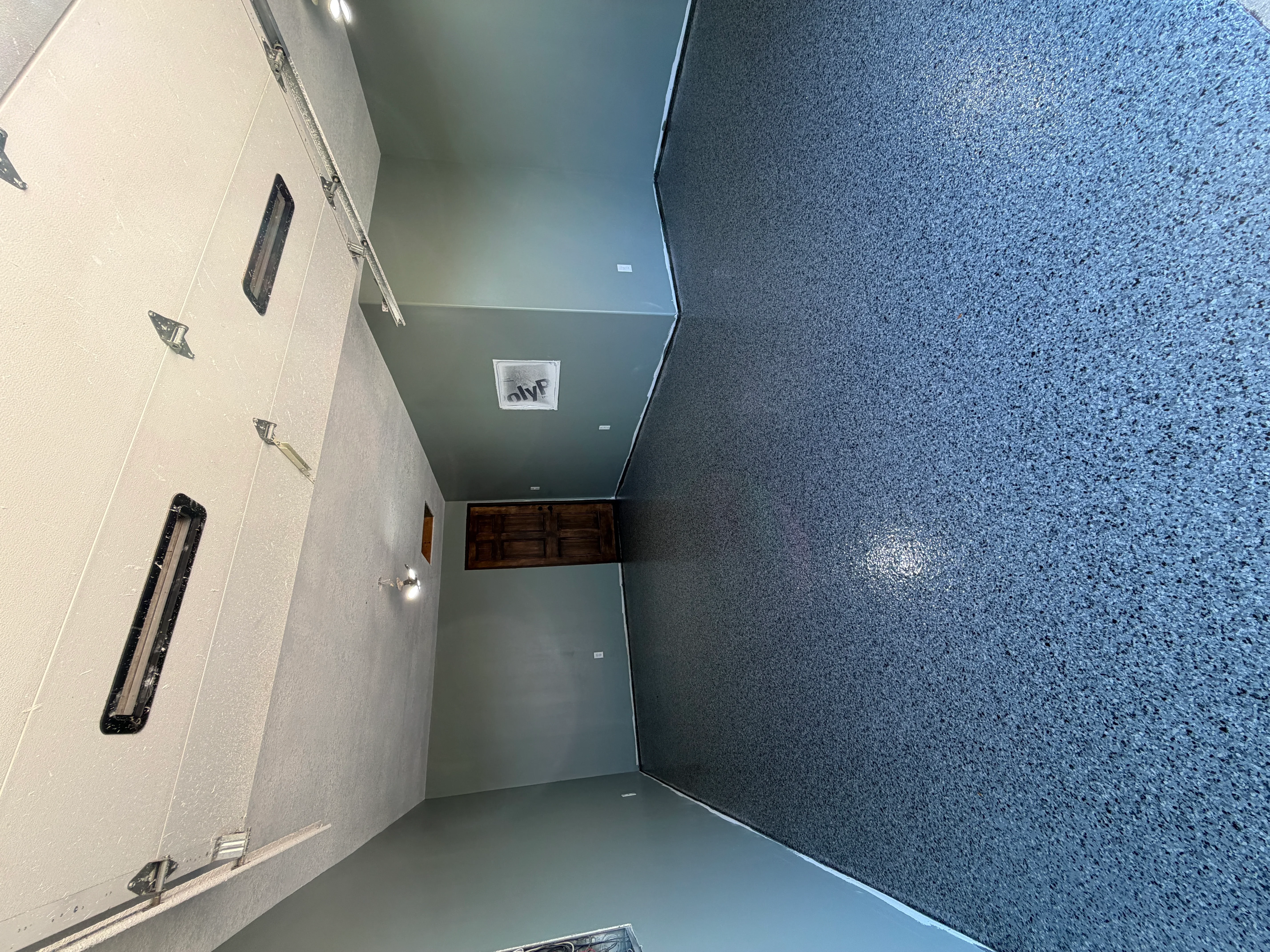 Slate blue concrete floor coating in commercial hallway with white walls and recessed lighting