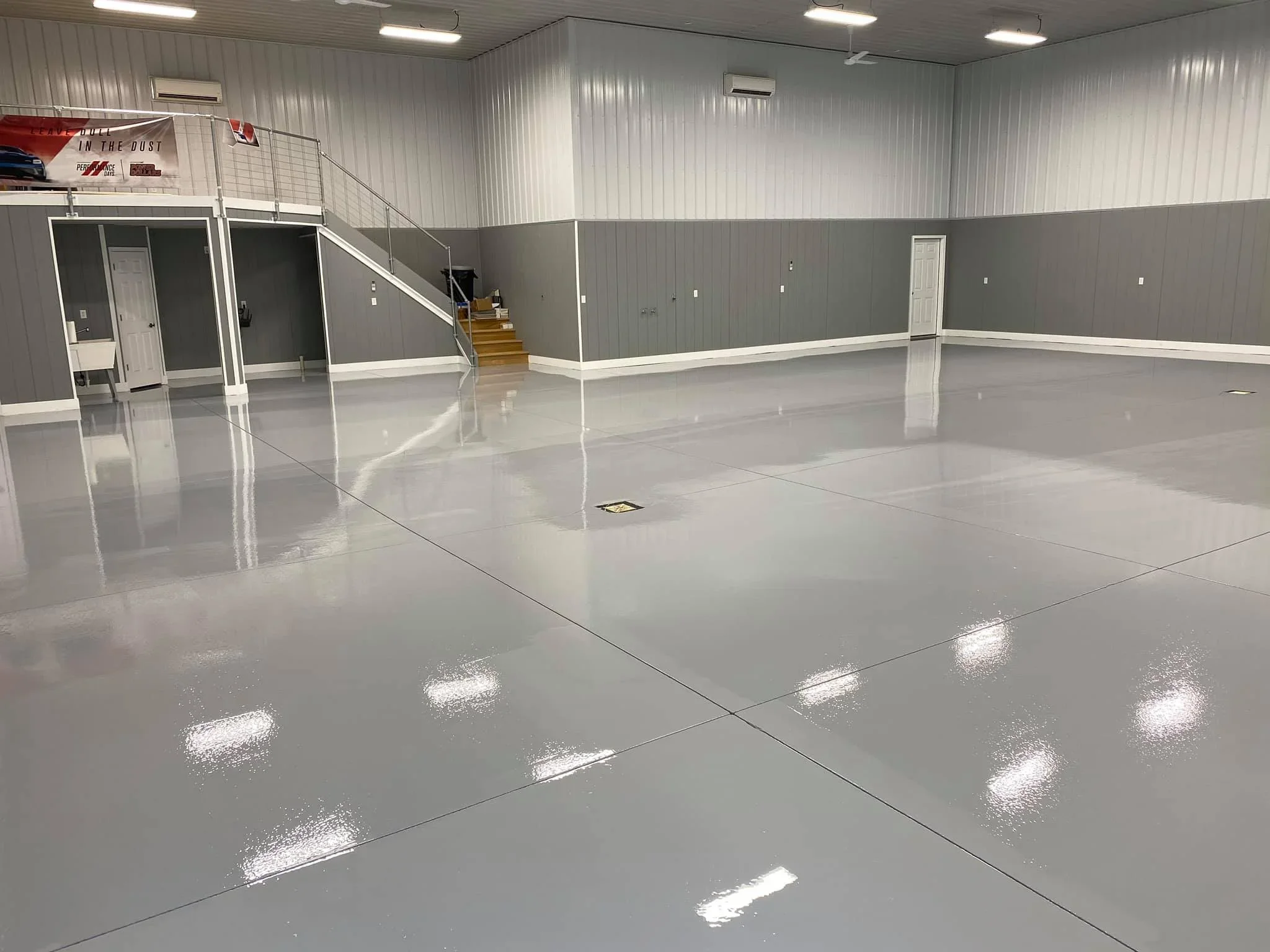 Polished gray epoxy warehouse floor with white trim and high-gloss finish