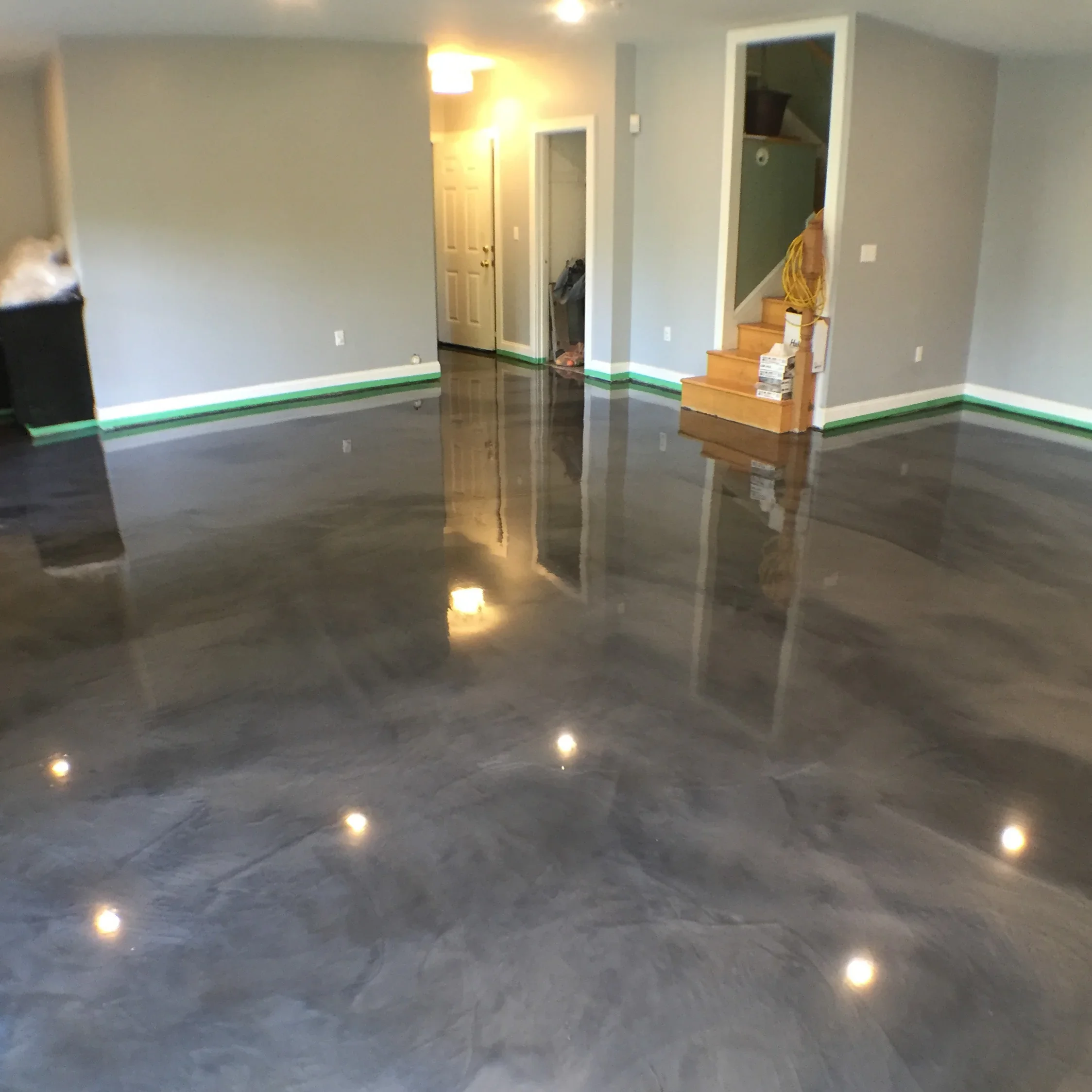 Polished concrete floor with glossy finish, green stripe trim, and recessed LED lighting in basement