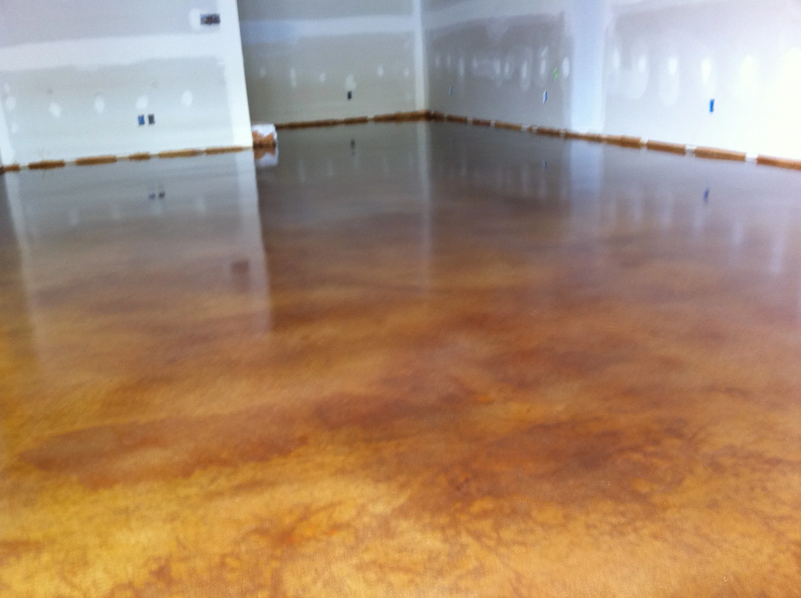 Metallic epoxy concrete floor with amber and bronze finish, high-gloss reflective surface