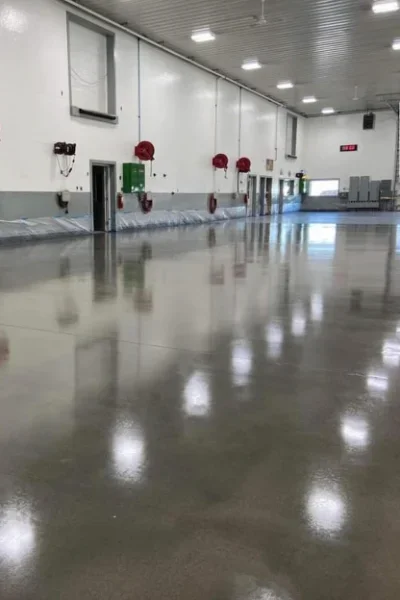 Polished epoxy-coated concrete gym floor with reflective finish and recessed ceiling lights
