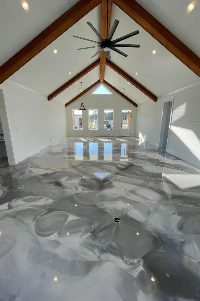 Polished gray epoxy concrete floor with marble pattern in vaulted room with wood beams